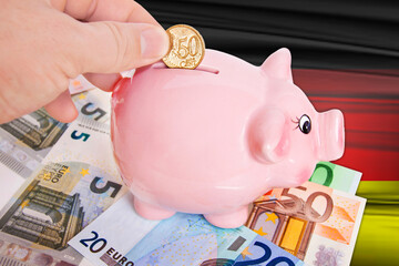 Sparschwein mit 50 Cent Euromünze auf Deutschlandflagge