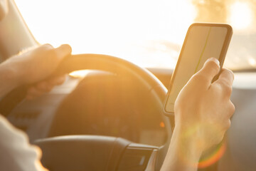 A tourist is sitting in a car and looking for the road in the Navigator app on a Sunny day