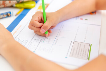 Close up of hand holding pencil and doing maths homework.