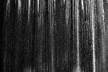 texture, crumpled plastic film on black with small splashes of water
