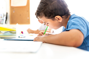Two boys studying and doing homework sitting at their desk in their bedroom at home