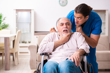 Old man in wheel-chair and young bad caregiver indoors