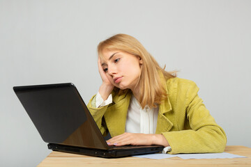 beautiful young female in a jacket at the table with a laptop