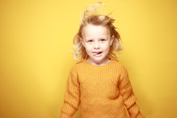 Petite fille qui fait des grimaces sur un fond jaune