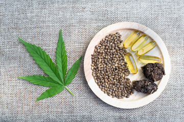 Cannabis leaves, wooden cups and tablets extracted from cannabis, a concept of alternative medicine, a natural medicinal herb. Biological and ecological cannabis.