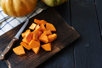 Cut pieces of raw pumpkin on wooden board on table