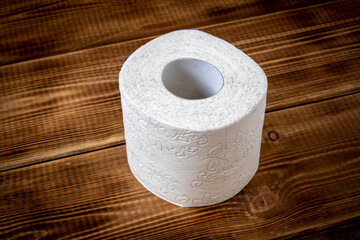 A roll of toilet paper on a wooden table. Close up.