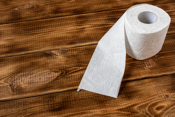 A roll of toilet paper on a wooden table. Close up.