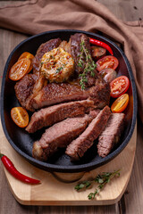 Fried beef steak with vegetables. A large piece of meat is sliced and garnished with fresh vegetables