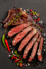 Fried beef steak with vegetables. A large piece of meat is sliced and garnished with fresh vegetables