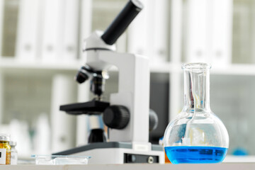 Microscope on the table with glassware in laboratory