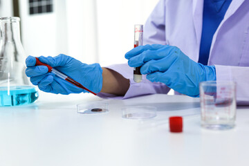 Scientist holding Coronavirus covid-19 infected blood sample tube DNA testing of the blood in the laboratory with blood sample collection tubes and syringe Coronavirus Covid-19 vaccine research.