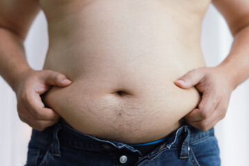 Naklejka premium Man with fat belly in dieting concept. Overweight man touching his fat belly and want to lose weight.
