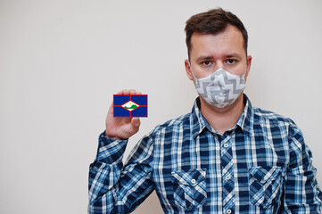 Man in checkered shirt show Sint Eustatius flag card in hand, wear protect mask isolated on white background. American countries Coronavirus concept.