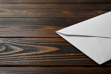 White paper envelope on wooden background, closeup. Space for text