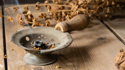 Incense burner fired with a match
on a wooden table. 
Walnut and basil in the background