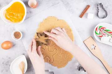 Christmas bakery. Woman making gingerbread, cutting cookies of gingerbread dough. Top view