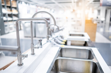 Male hand choosing stainless steel water tap in furniture store. Home improvement for domestic kitchen.