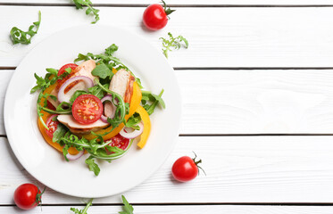 Delicious salad with chicken, vegetables and arugula on white wooden table, flat lay. Space for text