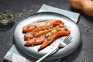 Baked slices of pumpkin with seasonings and feta on stone background