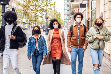 Obraz premium Group of multiracial friends walking on city street with protective face mask.