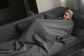 Man with white hair is sick wrapped in blanket at home