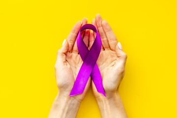 Purple ribbon alzheimer's disease pancreatic cancer or epilepsy awareness in hand. Top view