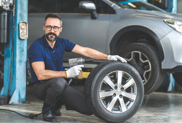 Obraz na płótnie Canvas Professional car mechanic changing car wheel at Car maintenance and auto service garage.