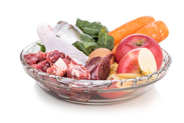 Ingredients of barf raw food recipe for dogs consisting meat, organs, fish, eggs and vegetable in white background