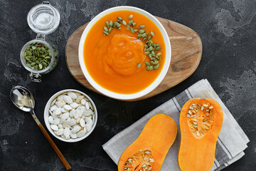 Top view of pureed pumpkin soup in a white bowl on dark table