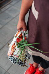 Zero waste concept with copy space. Female hand netting shopping bags with groceries. Eco-friendly shopping net. Free plastic concept. Delivery service.