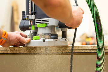 Man works with an electric milling cutter in a carpentry workshop