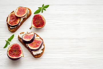 Toasted bread with figs, cheese and honey on table