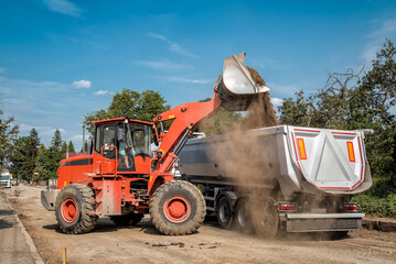 Obraz premium the loader loads the truck with gravel