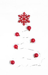 Christmas tree made of shiny ribbon, red baubles and snowflake on white. Top view. Stylized Christmas tree