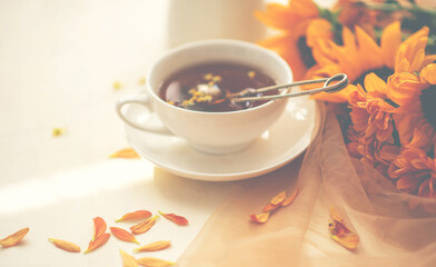 Autumn, fall leaves, flowers hot cup of herbal tea on wooden rustic background. Seasonal, morning tea. Sunday relaxing and still life concept. Toned image.