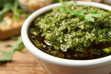 Bowl of tasty arugula pesto on table, closeup