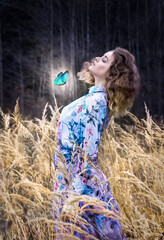 Beautiful girl in a blue dress in a field with butterflies. Wheat fields.