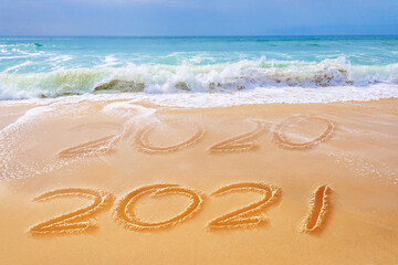 Fototapeta na wymiar 2021 written on the sand of a beach, travel 2021 new year concept and greeting card