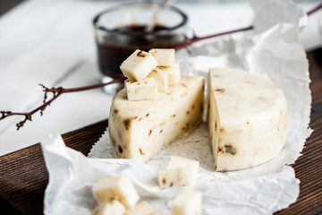 Milk products. Slice of Caciotta Al Tartufo cheese on a white wooden background. From homemade fresh milk. Clouse-up