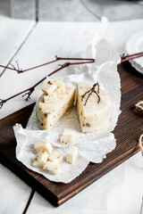 Milk products. Slice of Caciotta Al Tartufo cheese on a white wooden background. From homemade fresh milk