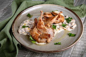 Quails in a creamy sauce with mushrooms. Still life in gray-green shades.