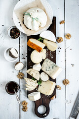 Various types of cheese. On a white wooden background. Blue cheeses with spices. Around honey and walnuts. Home cheese dairy. view from above