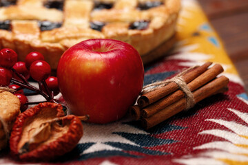 Tart pie with red apple and cinnamon on tablecloth