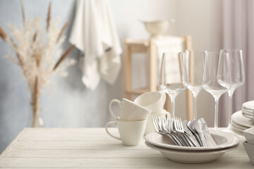Set of clean dishware, cutlery and wineglasses on white table indoors. Space for text