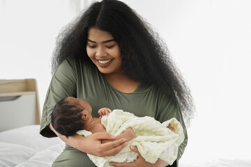 Portrait of African mom carrying adorable newborn baby in her arm. Happy lovely African American family mother and son at bedroom