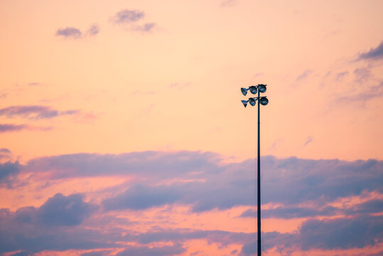 Single Pole Or Column Of Spotlight Or Stadium Light In Arena With Sunset Beautiful Sky And With Copy Space.