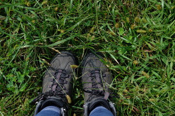 Looking down at brown hiking boots standing in the grass on a trail