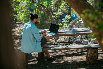 Fototapeta premium Male tourist working on a laptop outdoors in a camping.