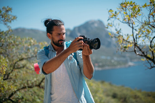 Male tourist, photographer in a mountain grove overlooking the sea